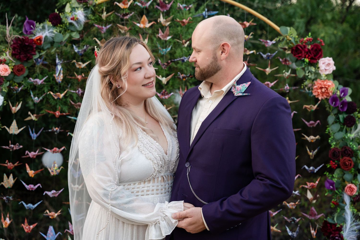 A couple shares an intimate moment in front of a butterfly-decorated arch at their wedding.