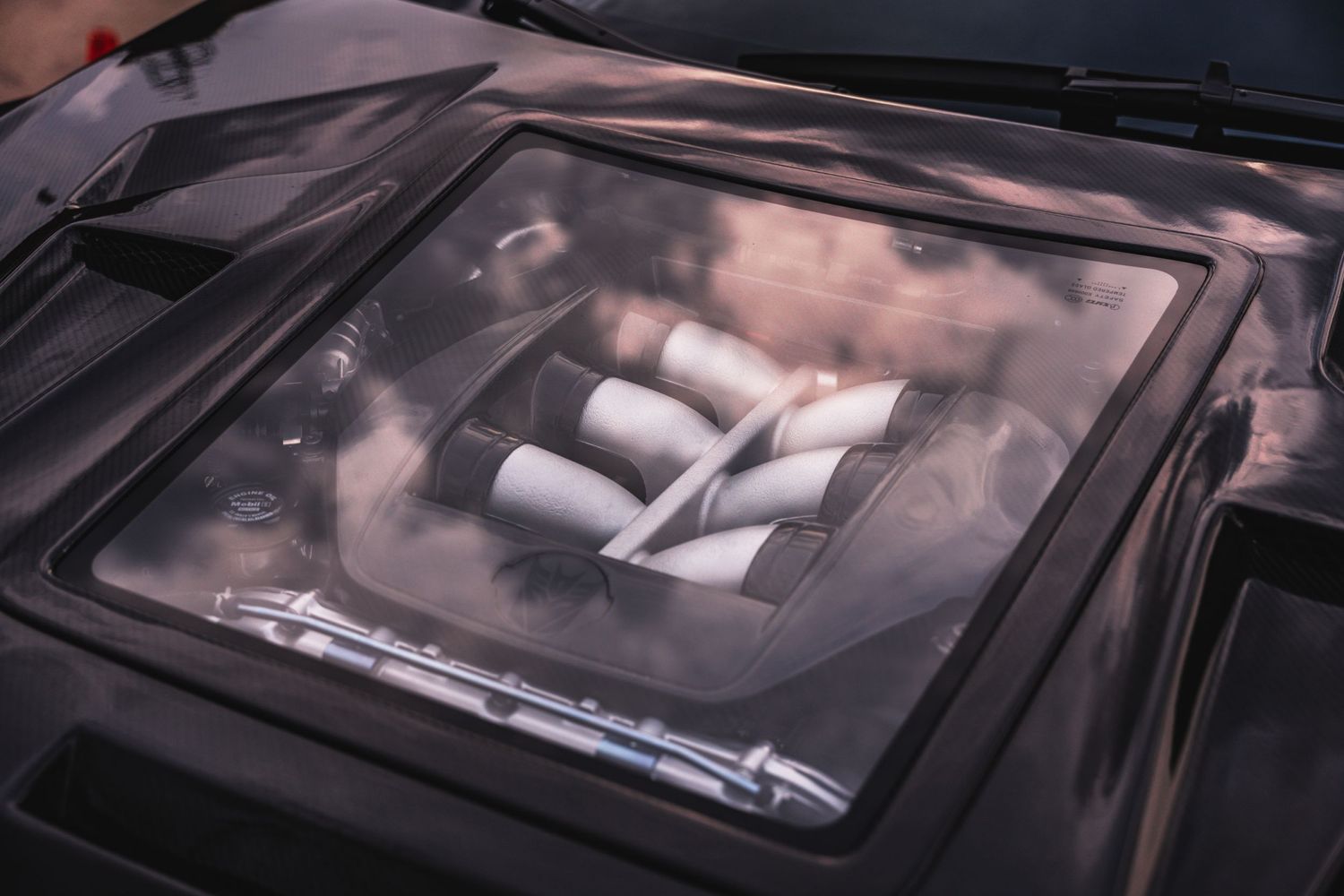 Close up of a car hood window showing engine components beneath.