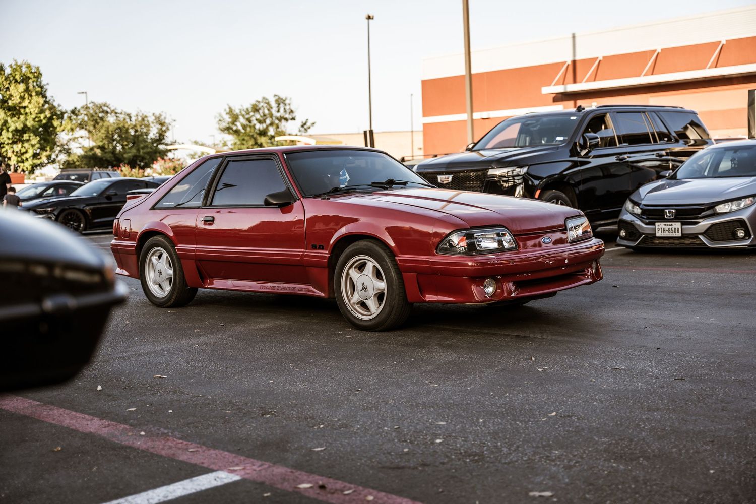 A red Chevrolet Monte Carlo SS parked in a lot during a car meet.