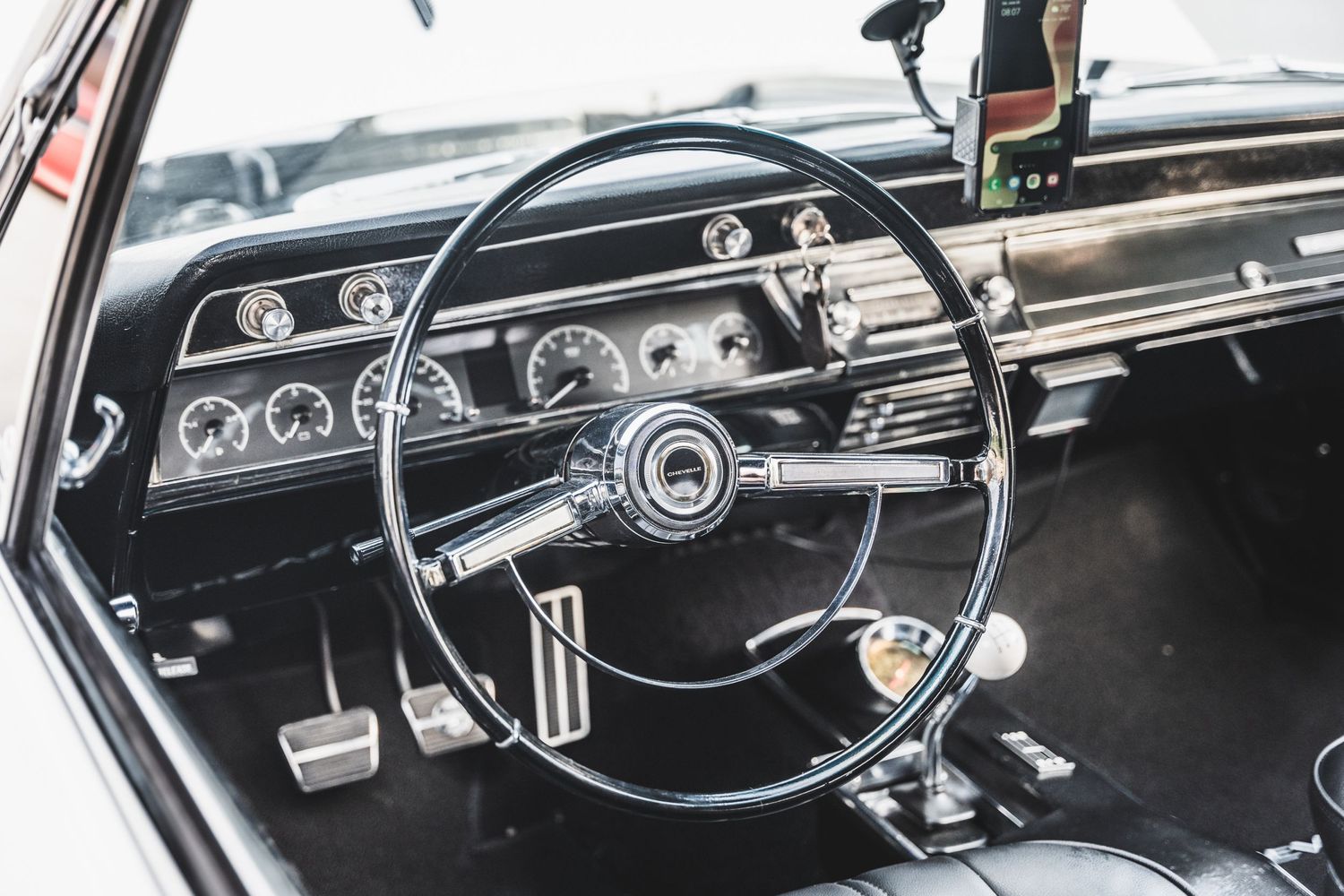 Vintage black dashboard and steering wheel of classic American muscle car interior.