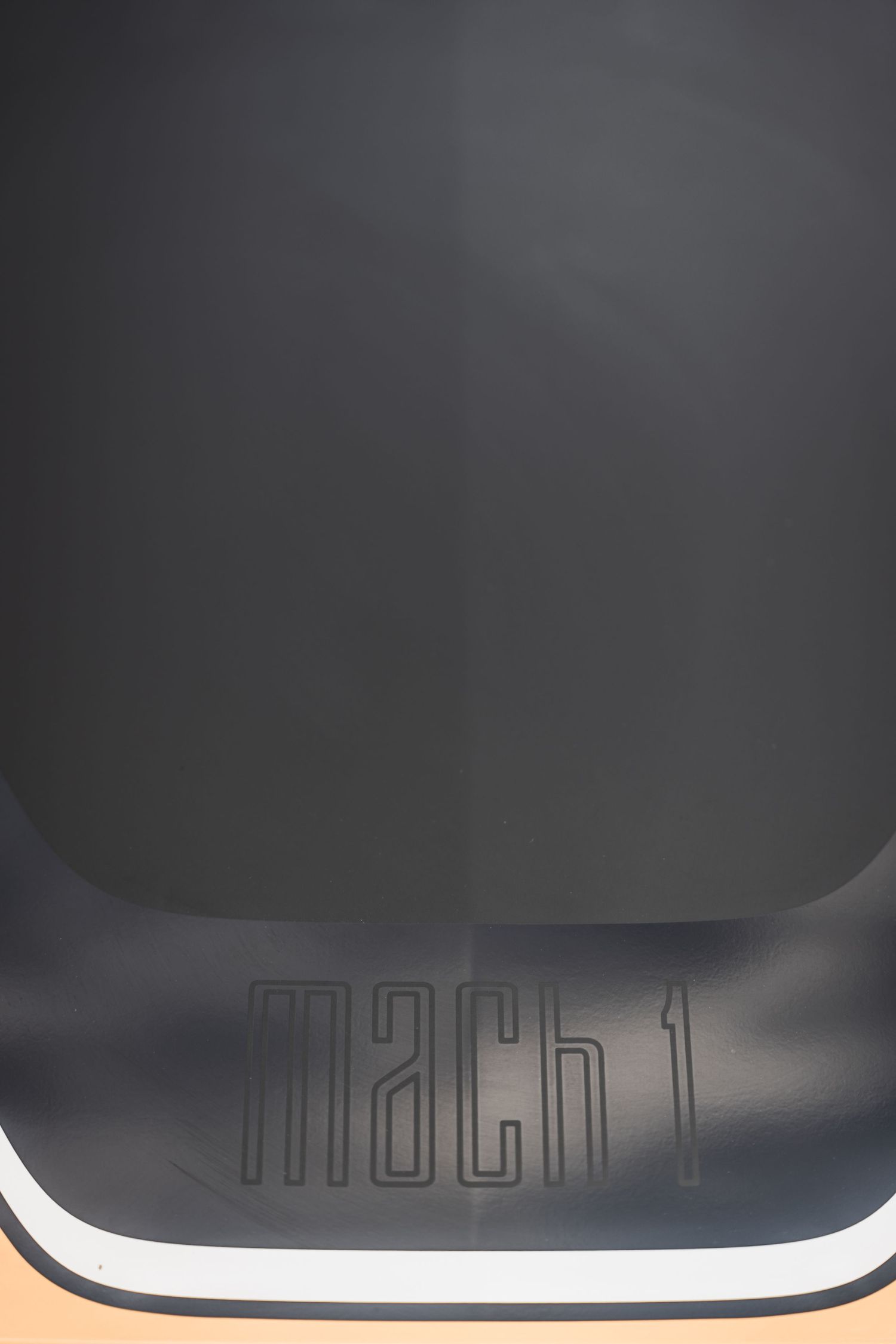 Close-up of black Mach 1 branding detail on what appears to be a vehicle panel.