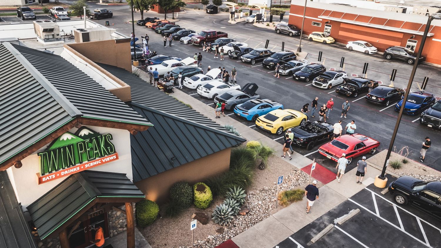 Aerial view of cars parked outside a restaurant during a car meet.