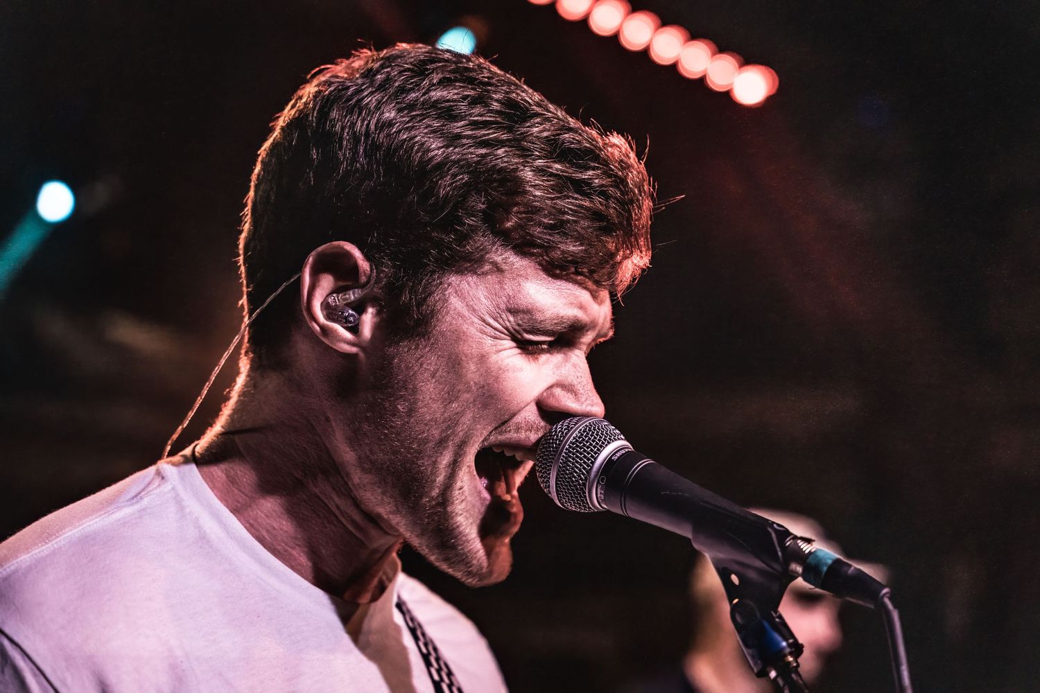 Passionate musician performs with intense emotion at a concert under dramatic lighting.