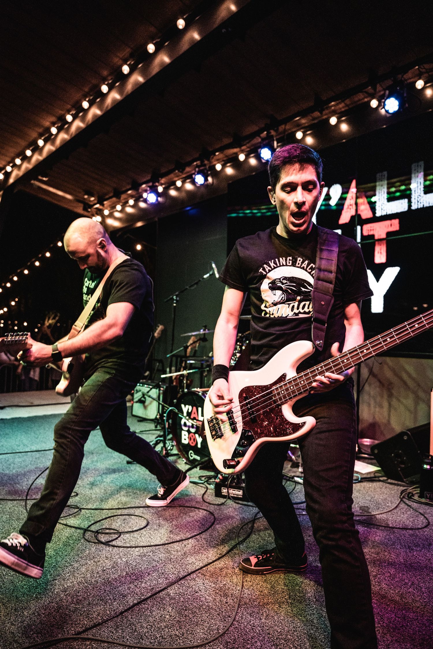Rock musicians performing with guitars on concert stage under theatrical lighting.