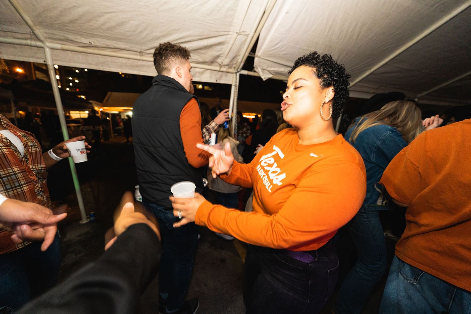 People dancing and enjoying themselves at covered outdoor party.