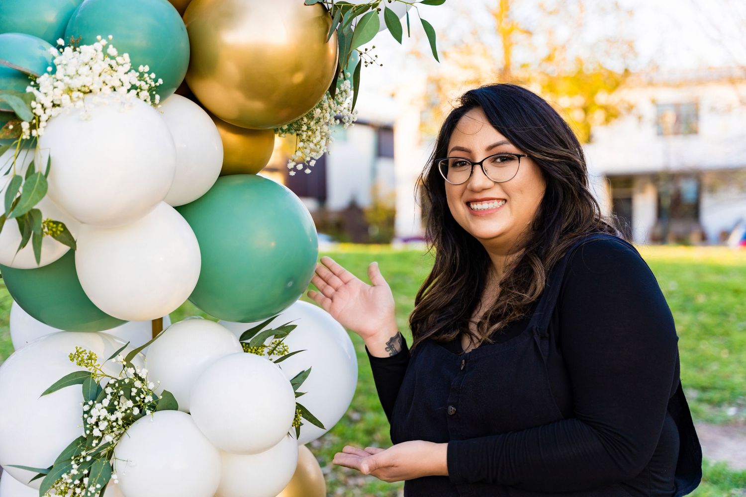 Person gesturing beside an elegant balloon arrangement featuring gold, mint and white colors.