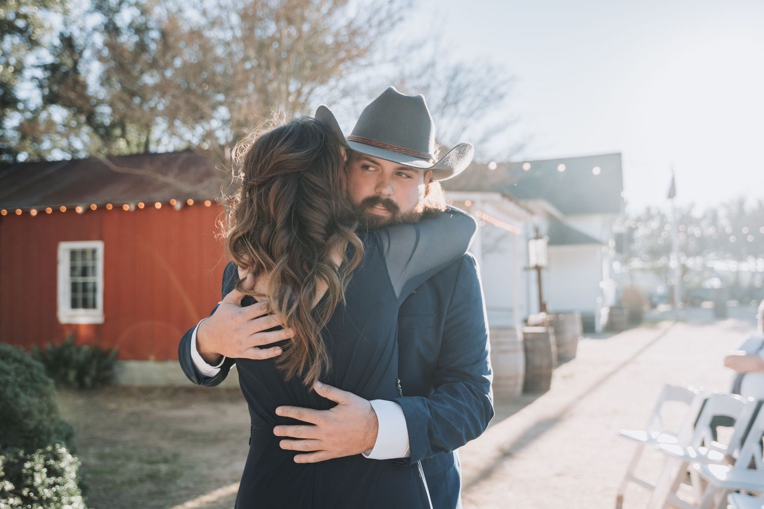 A tender embrace between two people during an outdoor wedding celebration.