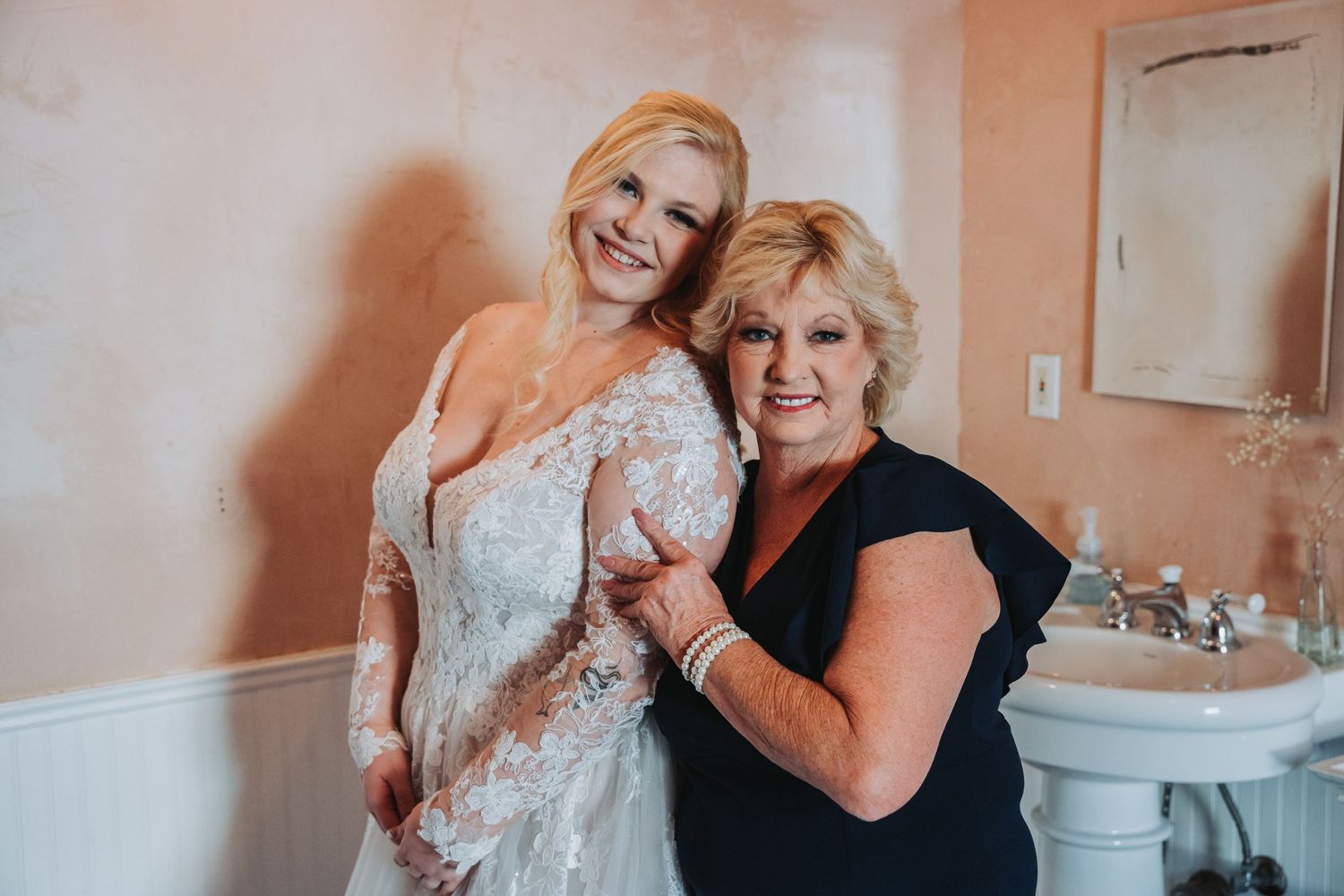 A joyful moment shared during wedding preparation in a peach-colored room.
