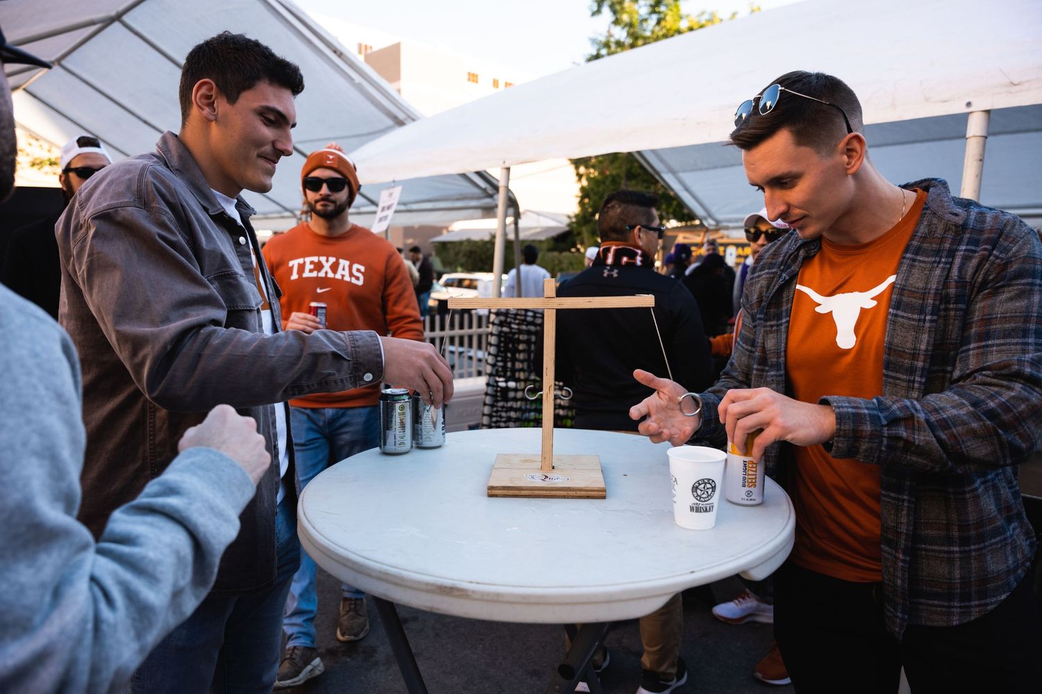 People gathered around a white table playing games at an outdoor event.