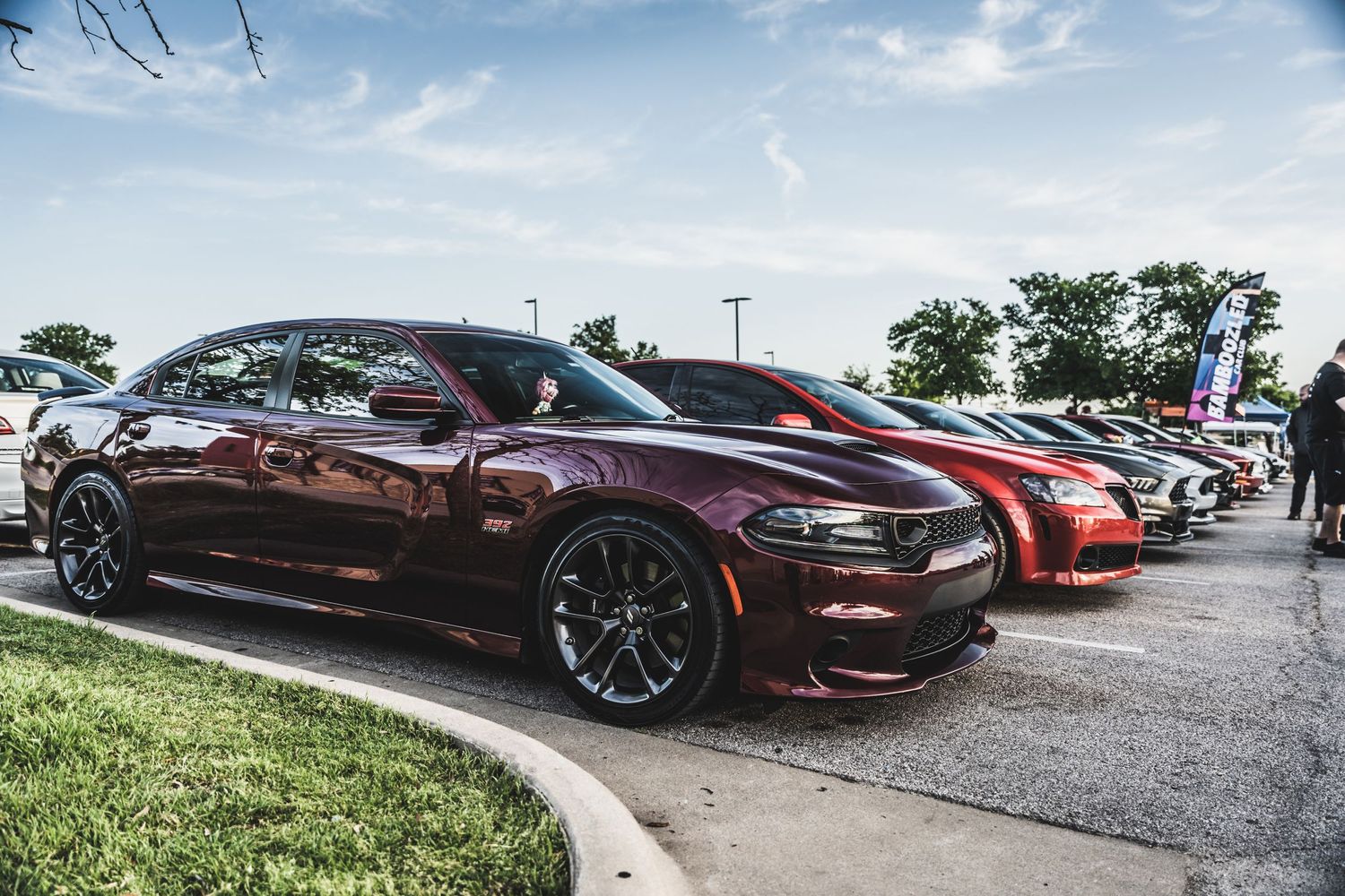 Maroon and red performance vehicles with custom wheels displayed at a car meet.