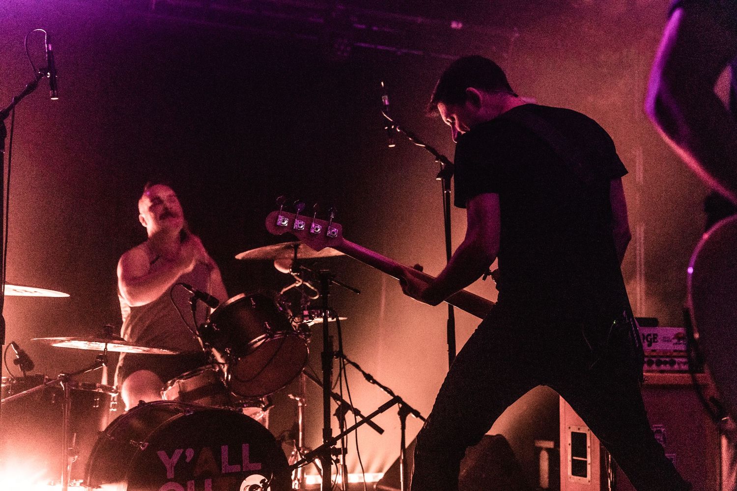 Silhouetted band members play drums and guitar during atmospheric rock performance.