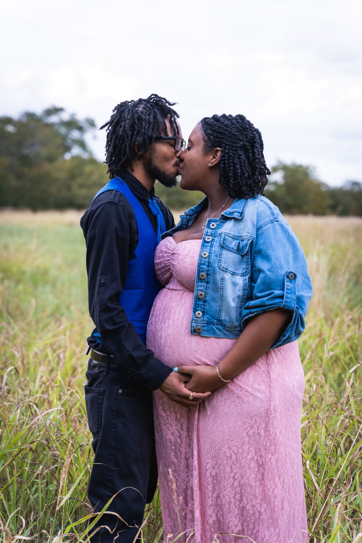 A tender moment captured during a maternity photoshoot in a tall grass field.