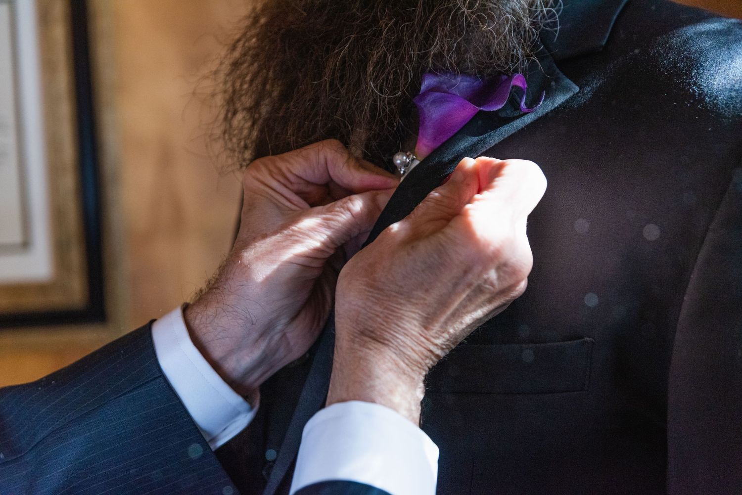 Hands adjusting a purple bowtie on formal attire.