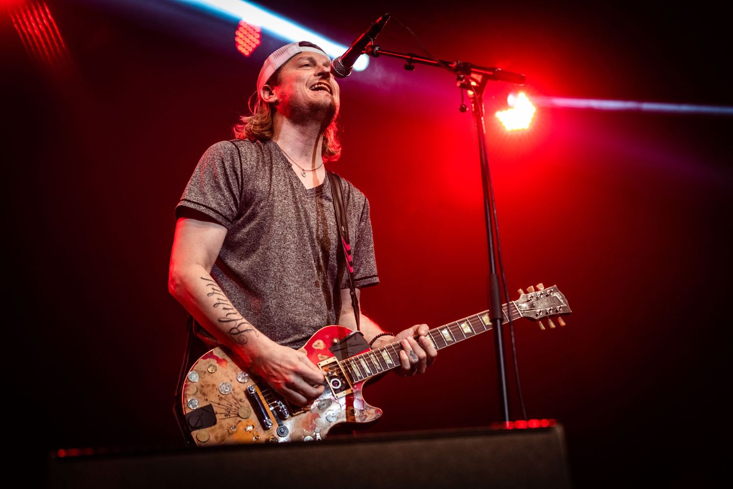 Rock musician performs with vintage guitar under dramatic red stage lighting.