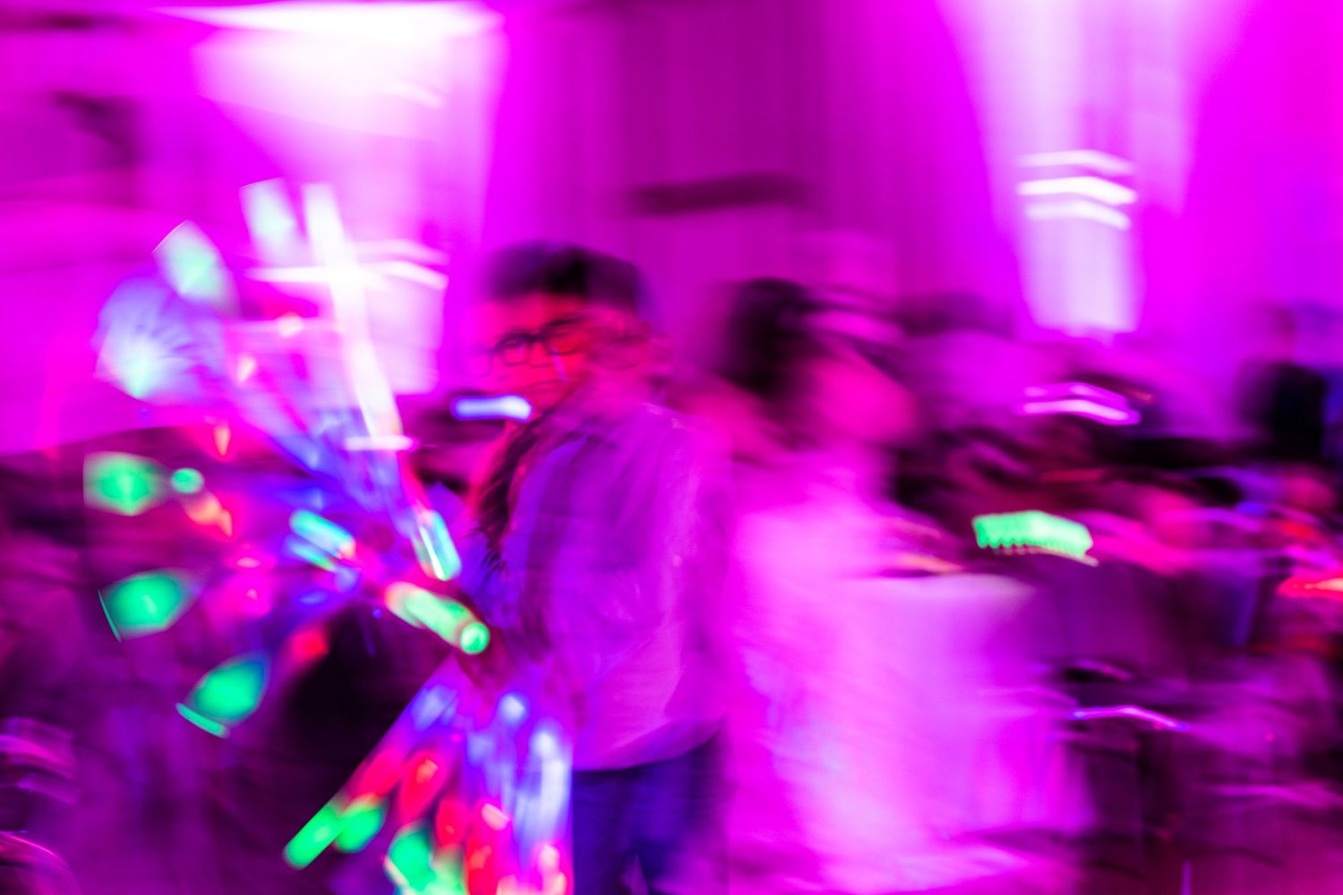 Abstract motion blur photo with purple lighting and colorful streaks at a dance party.