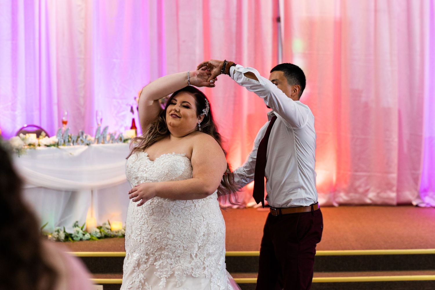 Wedding celebration dance moment captured under pink ambient lighting.