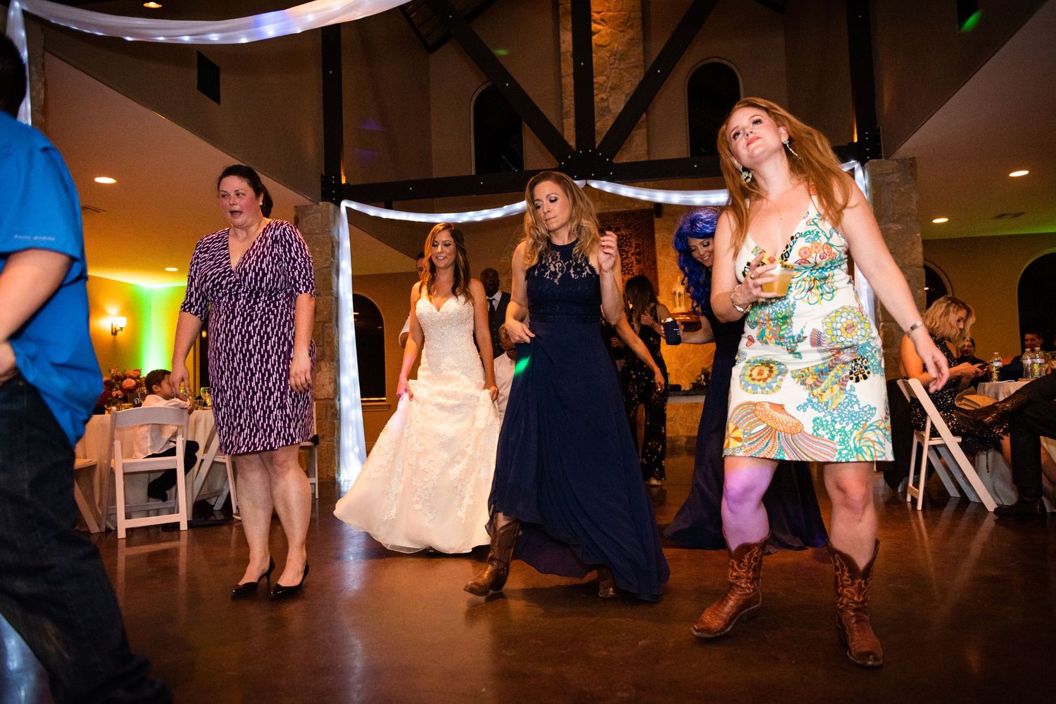 Wedding guests dancing enthusiastically on the reception dance floor.