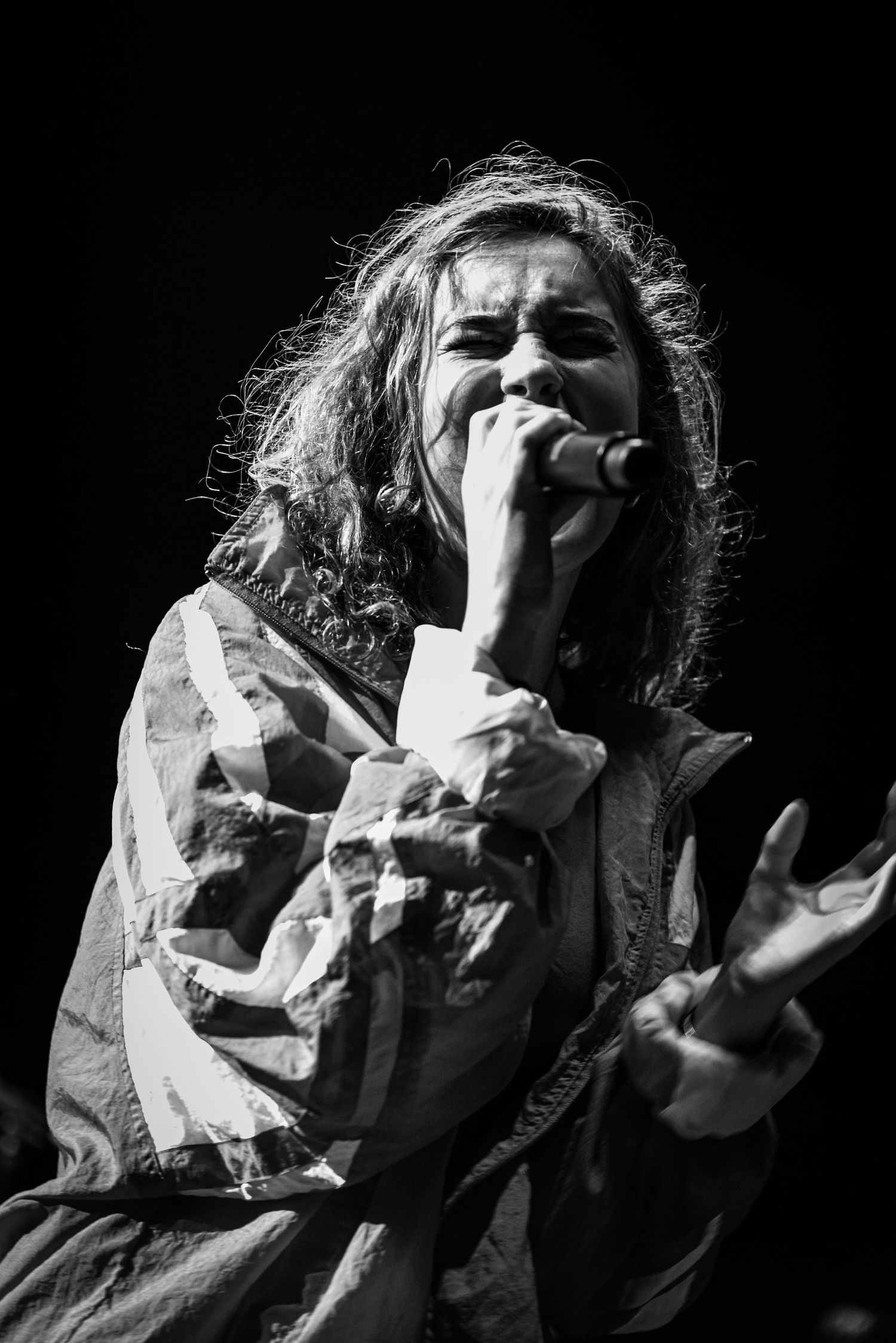 Dramatic black and white photo of a performer singing passionately on stage.
