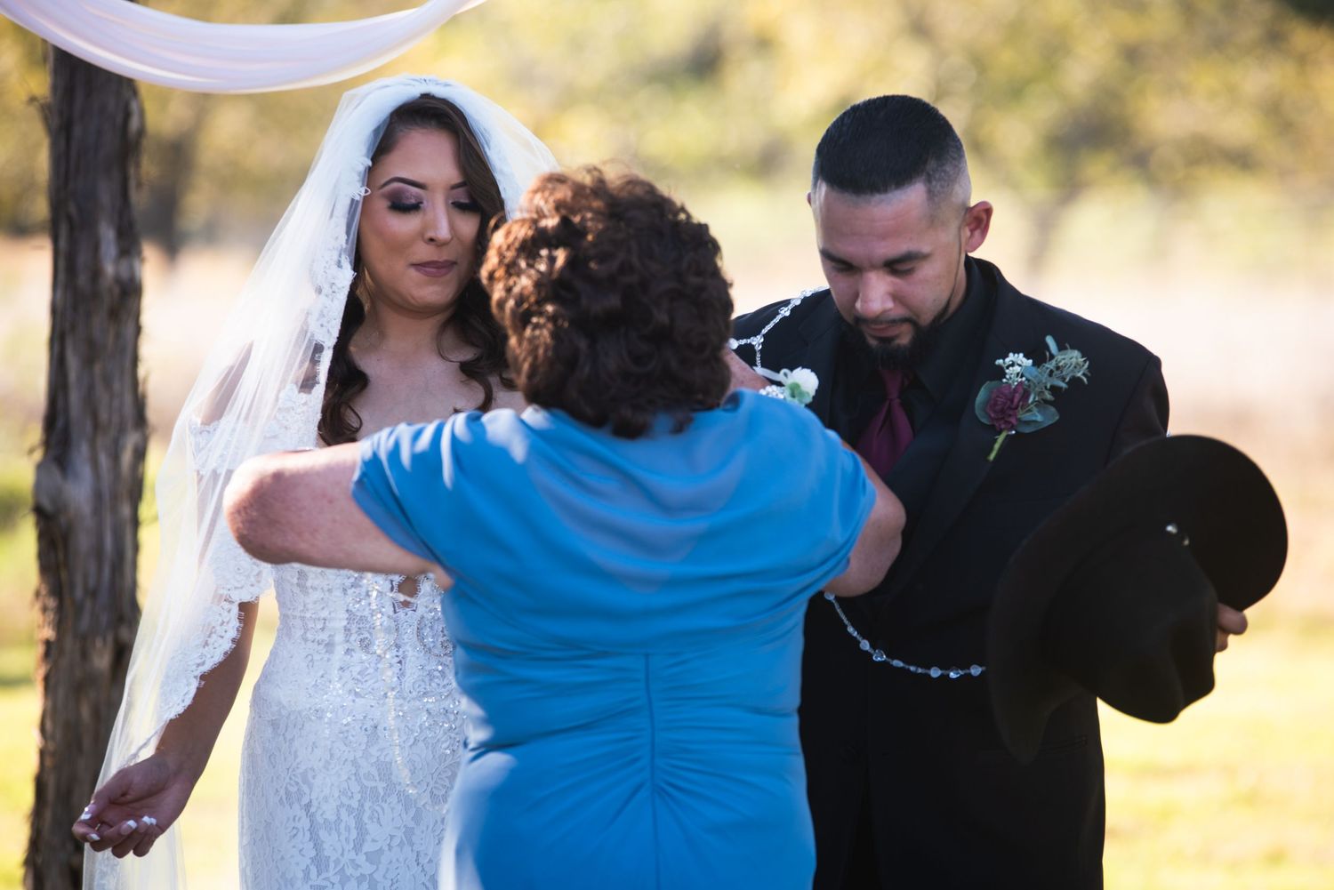 Wedding ceremony embrace under natural sunlight at outdoor venue.