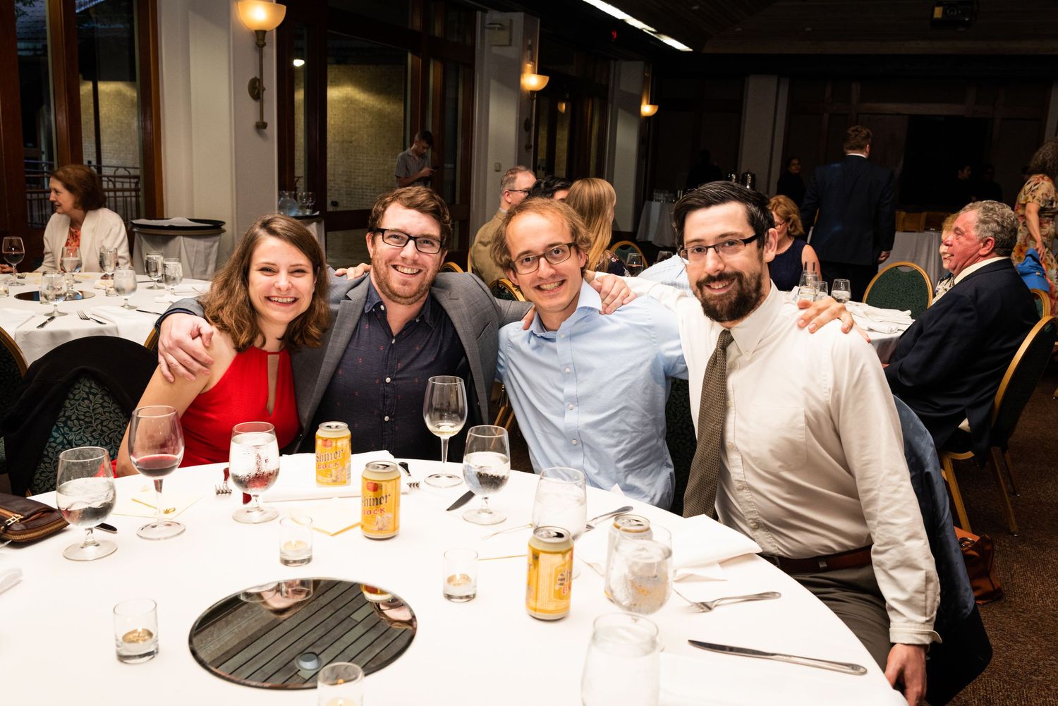 A group of wedding guests enjoying dinner and drinks at a reception table.