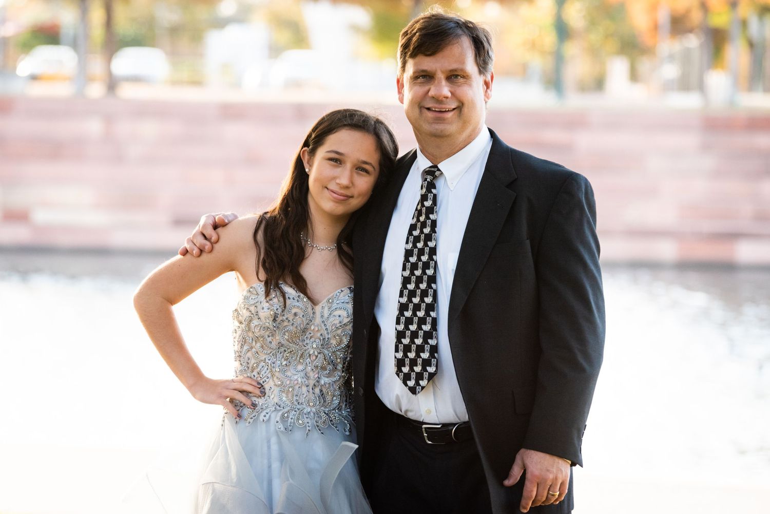 Father-daughter portrait outdoors showing special bond and formal attire.