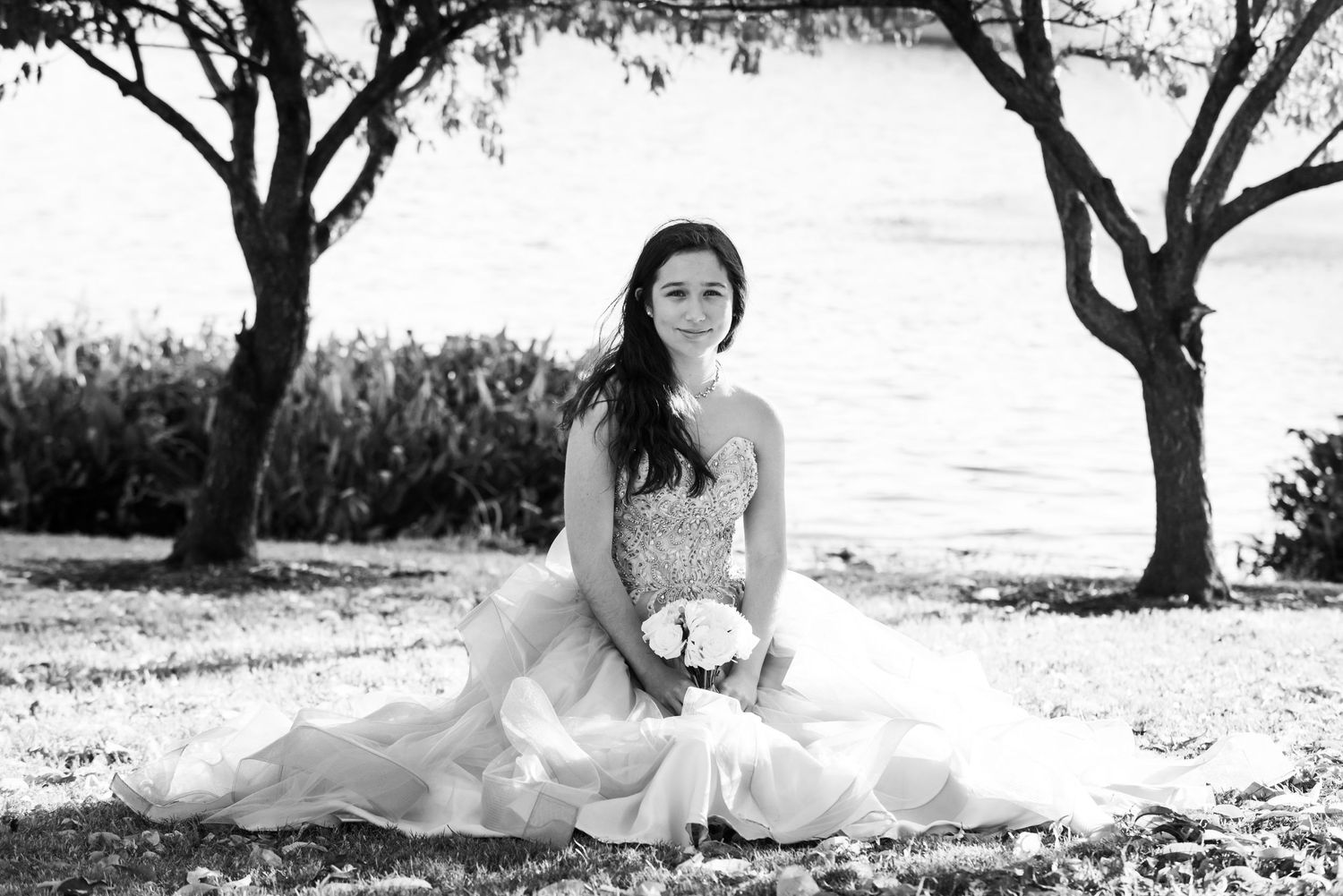 Classic black and white photograph of a bridal portrait in a garden setting with trees.