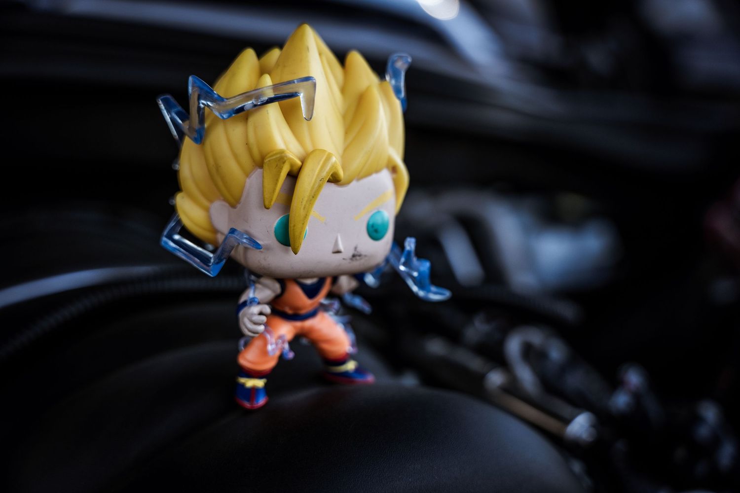 Small anime-style figurine with spiky yellow hair displayed on dark surface.