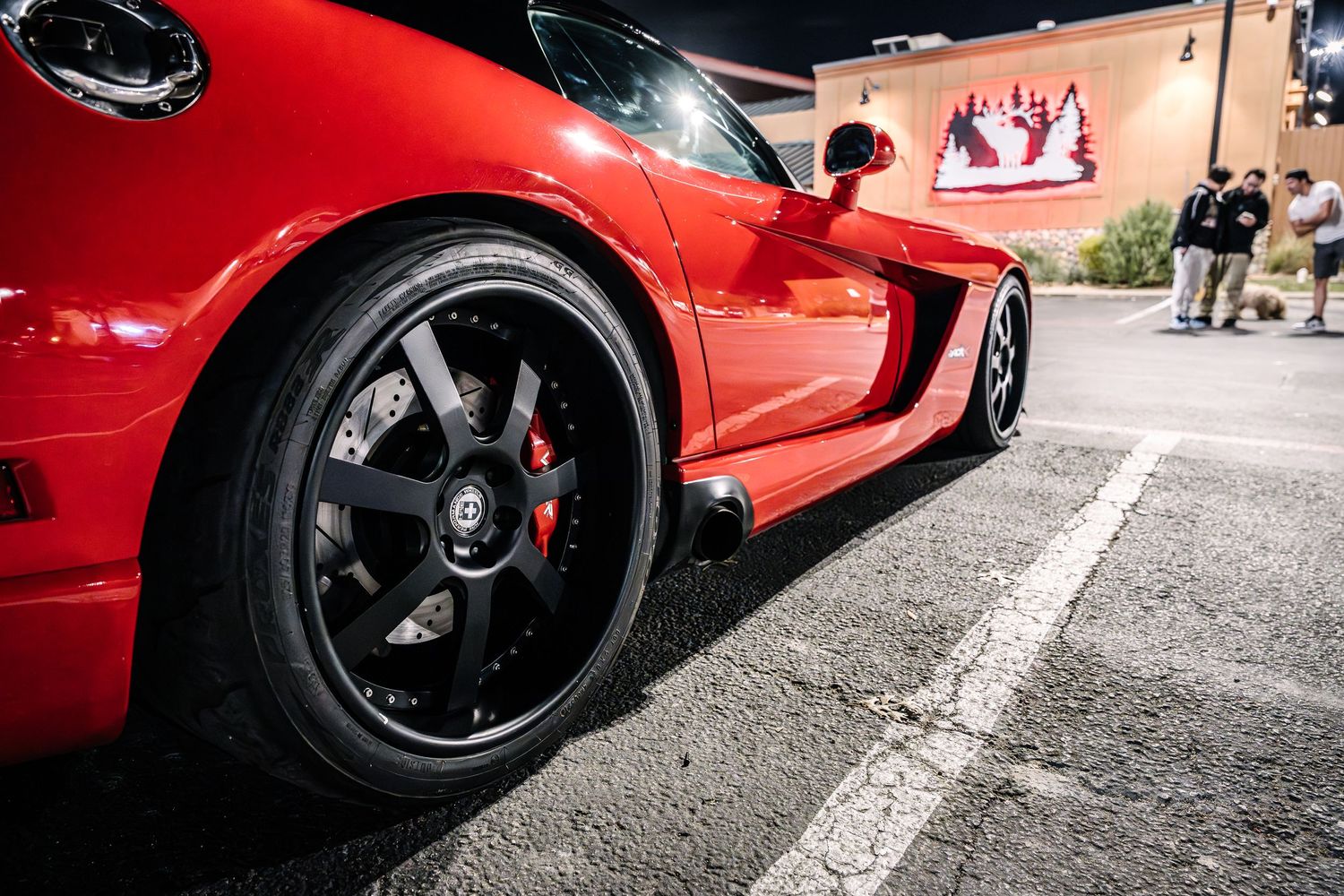 Close-up view of a red sports car with black wheels and performance brakes.