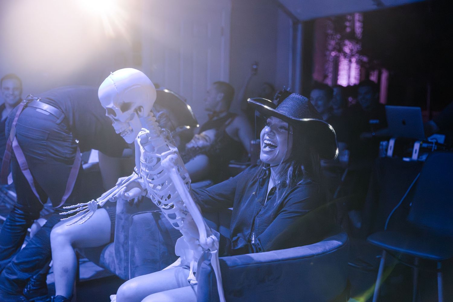 People enjoying a performance in a dimly lit venue with blue atmospheric lighting.