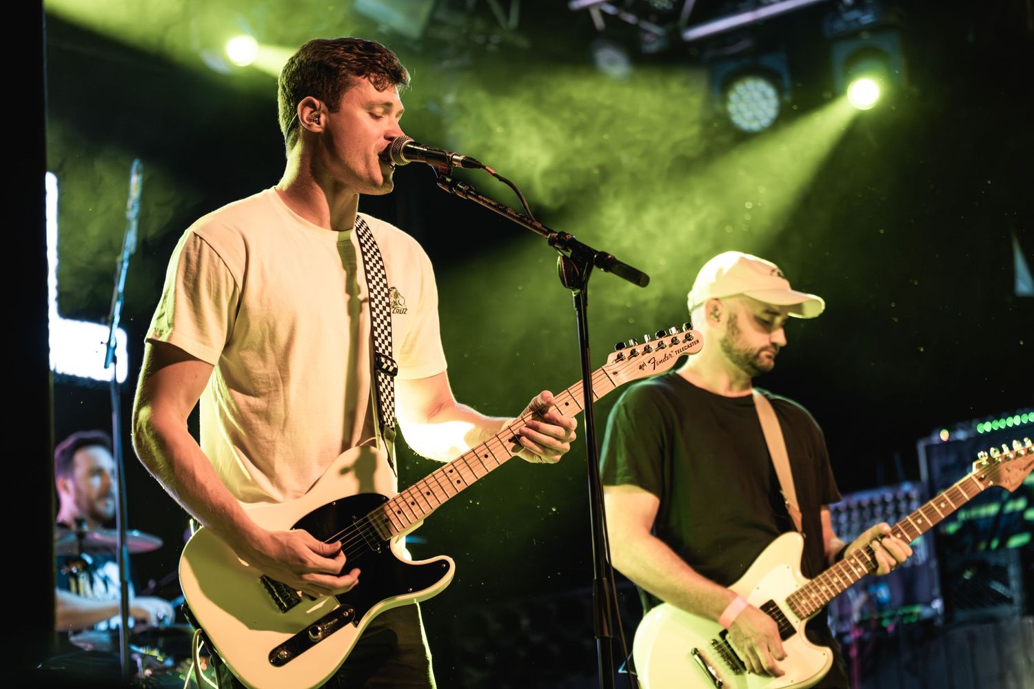 Musicians perform under green stage lighting during live concert.