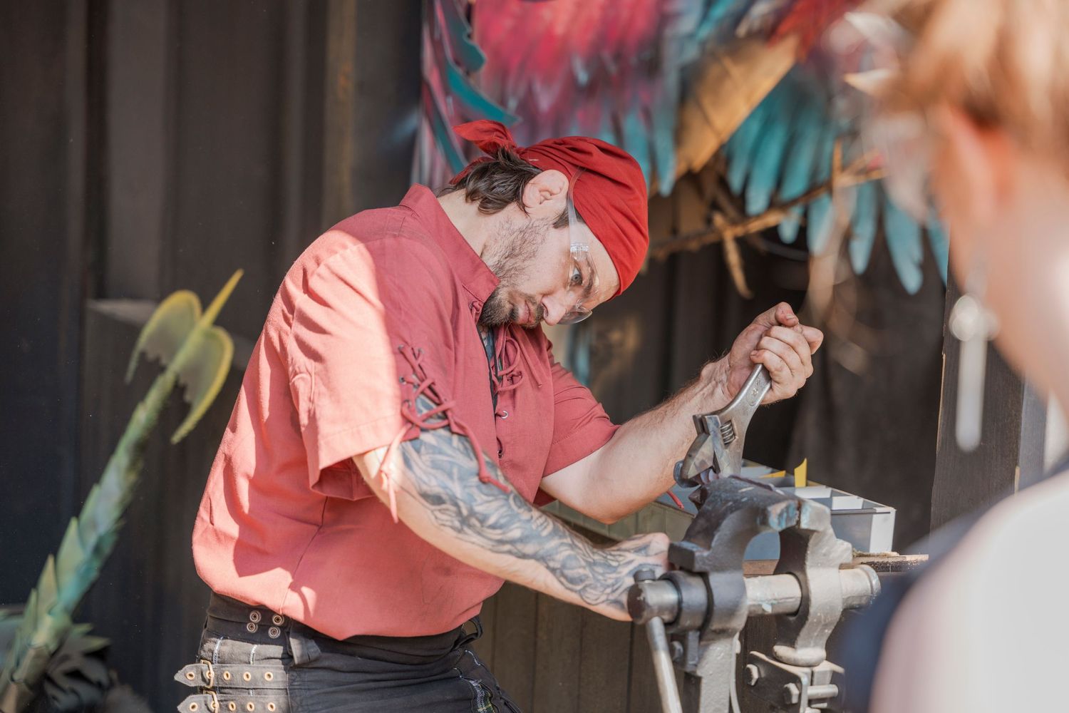Craftsperson working with metal tools at a Renaissance festival demonstration booth.