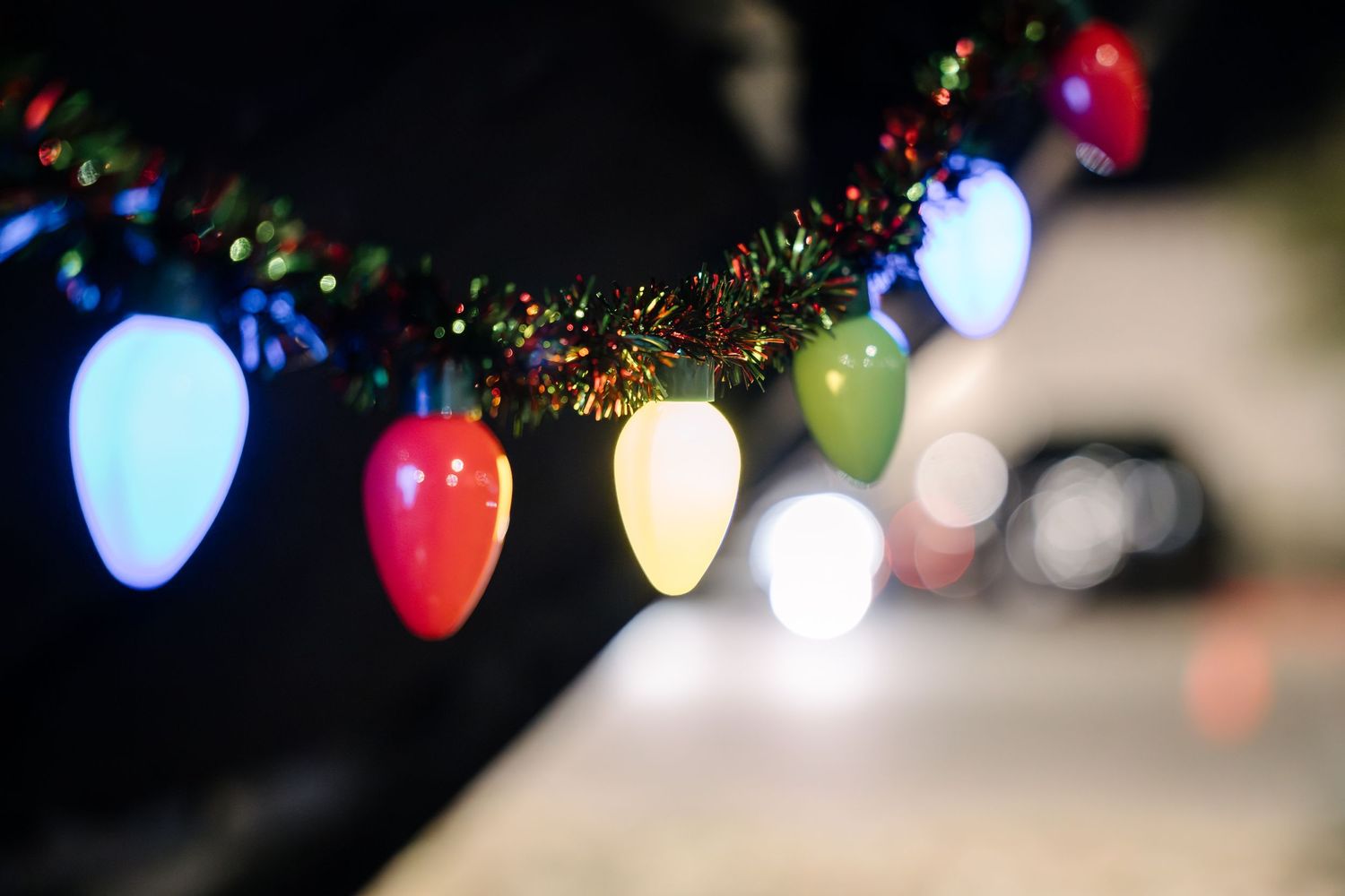 Decorative string of colorful Christmas light bulbs with bokeh effect.