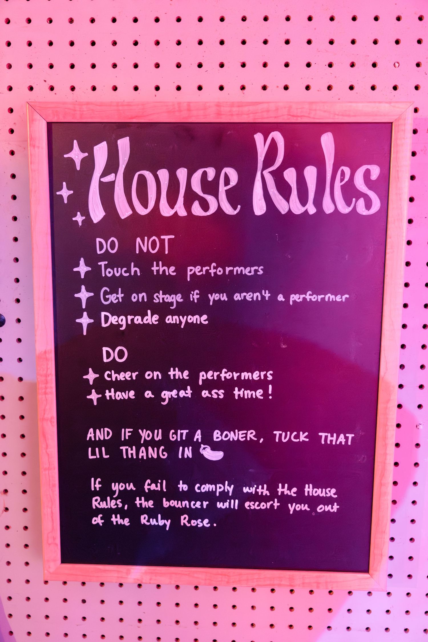 Pink house rules sign listing venue guidelines and policies for performers and guests.