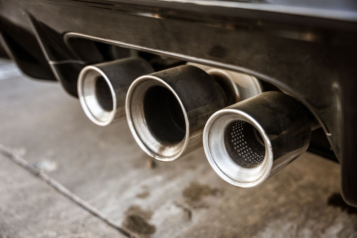 Triple exhaust tips detail shot showing polished stainless steel finish.