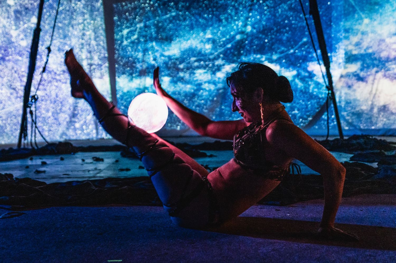 Artistic performance with glowing orb prop against celestial blue backdrop.