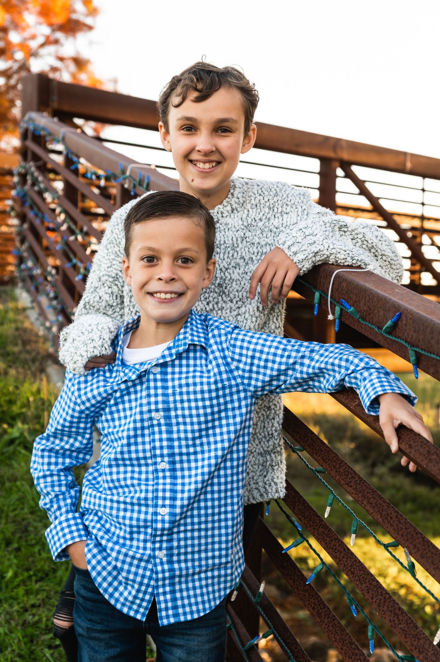 Two people posing together on wooden bench during fall season.