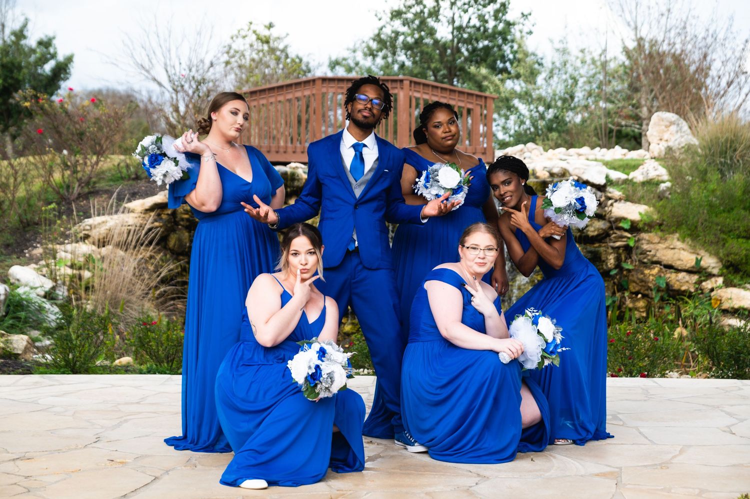 Wedding party strikes dramatic poses outdoors wearing coordinated royal blue formal attire.