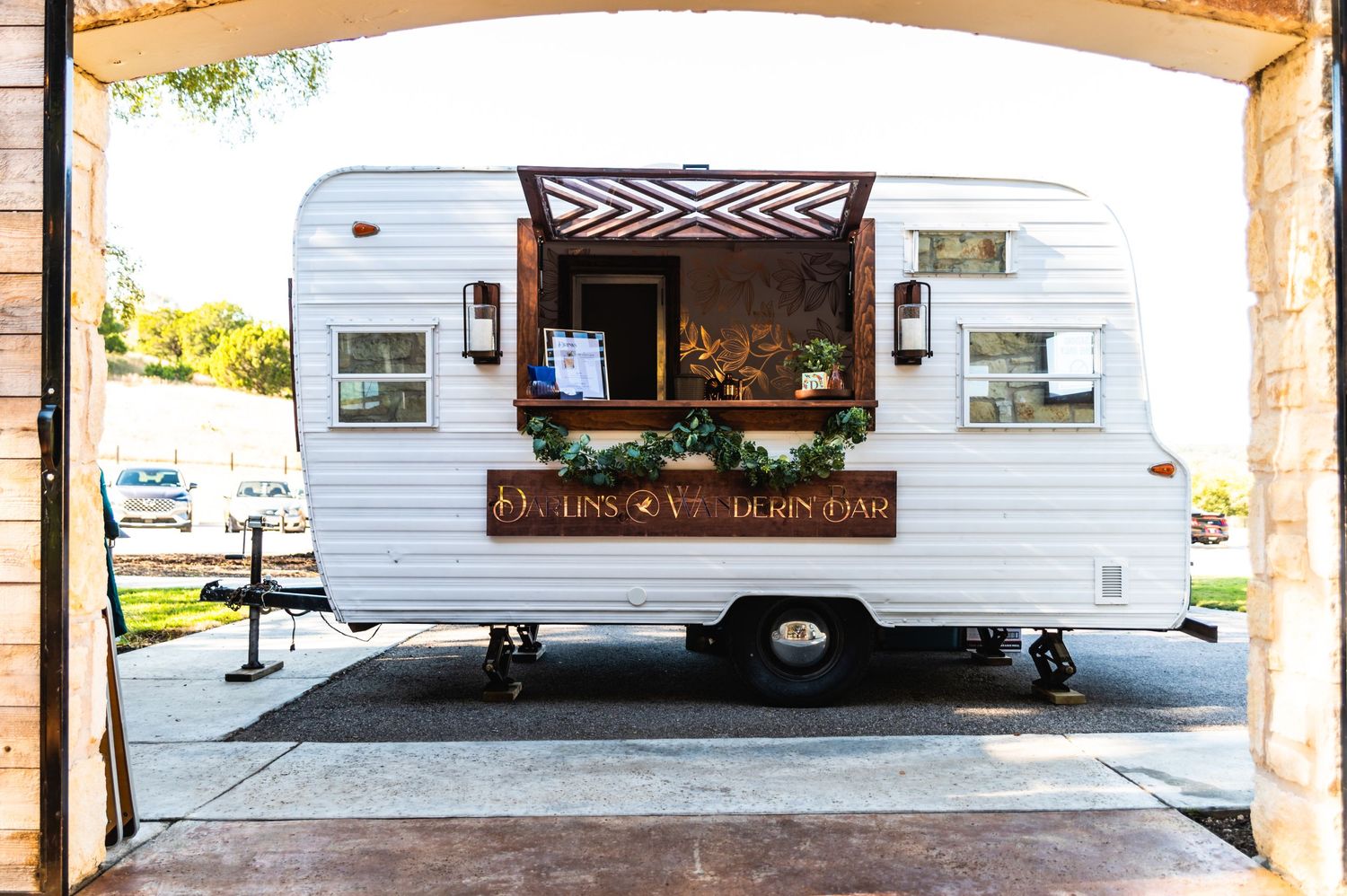 Vintage white food truck with serving window parked under covered area.