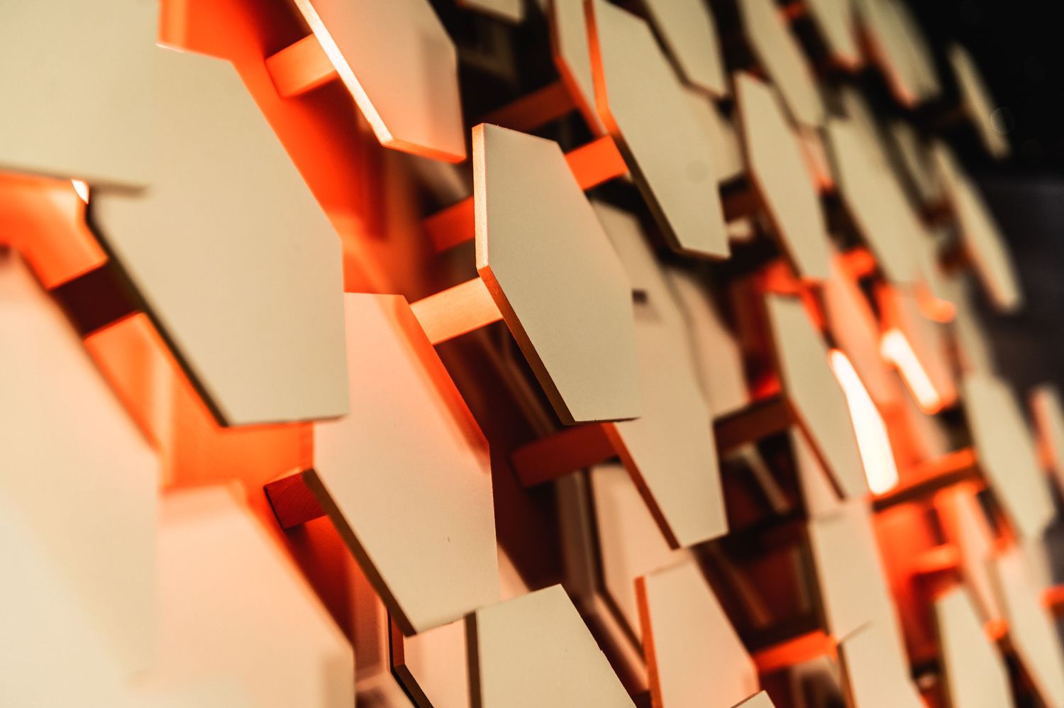 Close-up detail of illuminated orange hexagonal wall panels creating geometric patterns.