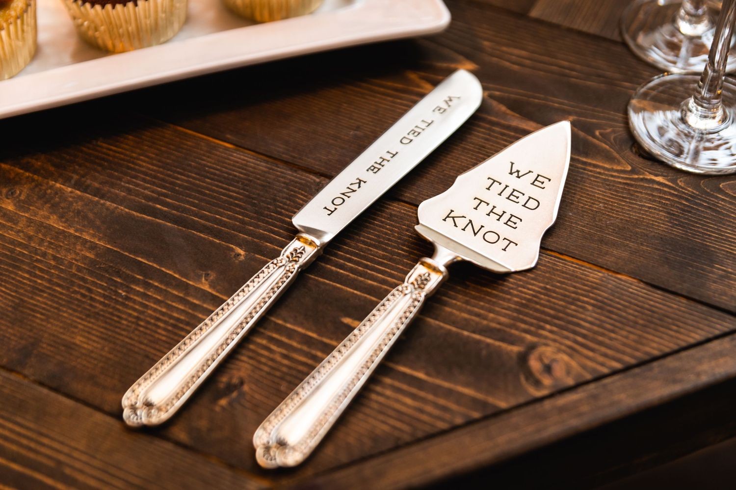 Vintage-style cake serving utensils with engraved messages on wooden table.