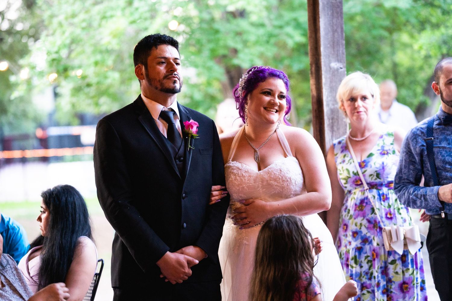 A couple shares a sweet moment during their wedding celebration as guests look on.