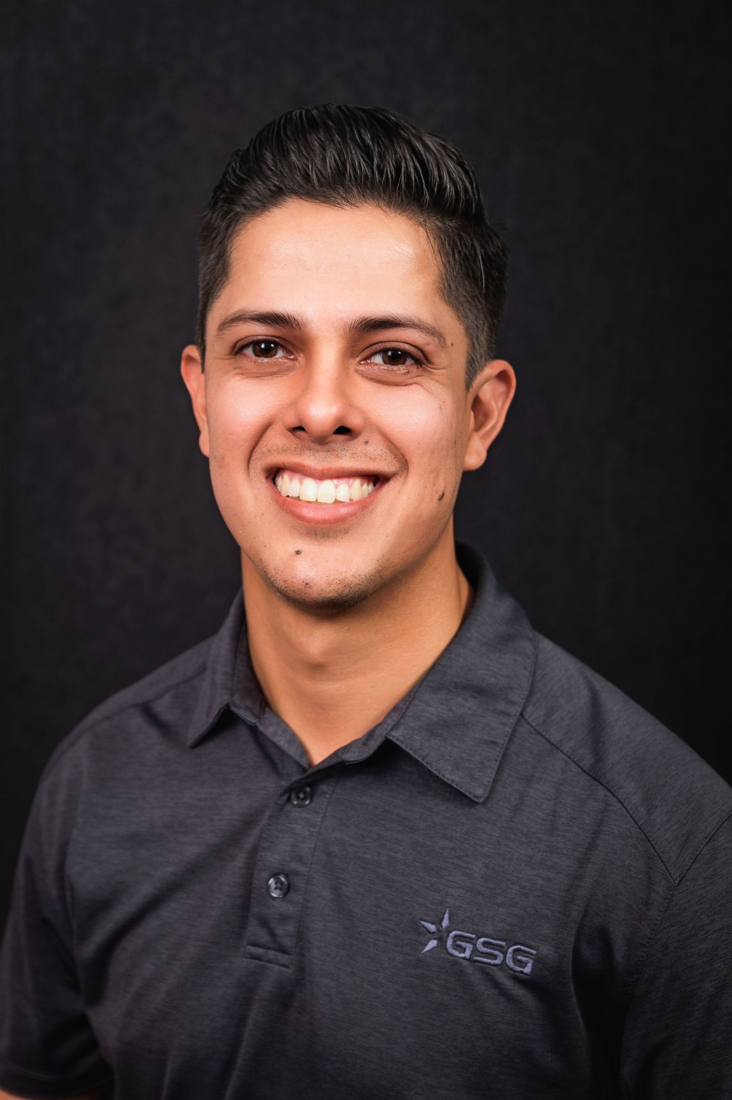 Close up professional portrait of smiling person in gray polo shirt with GSG logo.
