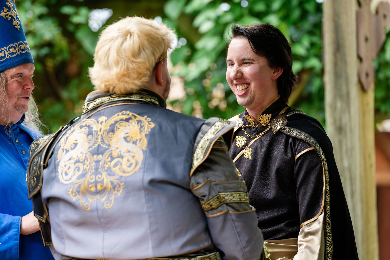 People in medieval or renaissance period costumes engage in friendly conversation outdoors.