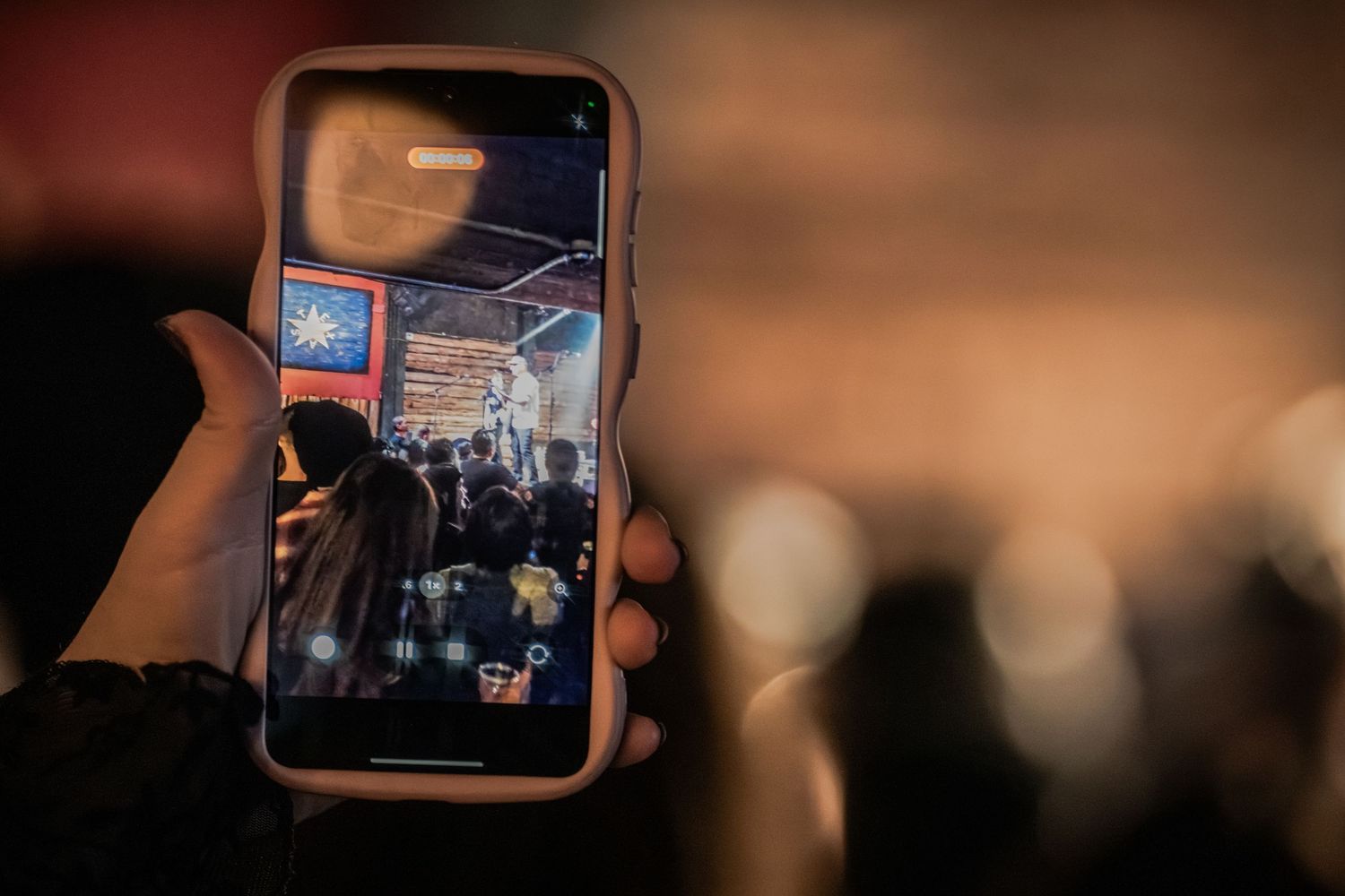 A person holds up a mobile device displaying a dark screen with glowing interface elements in a dimly lit environment.