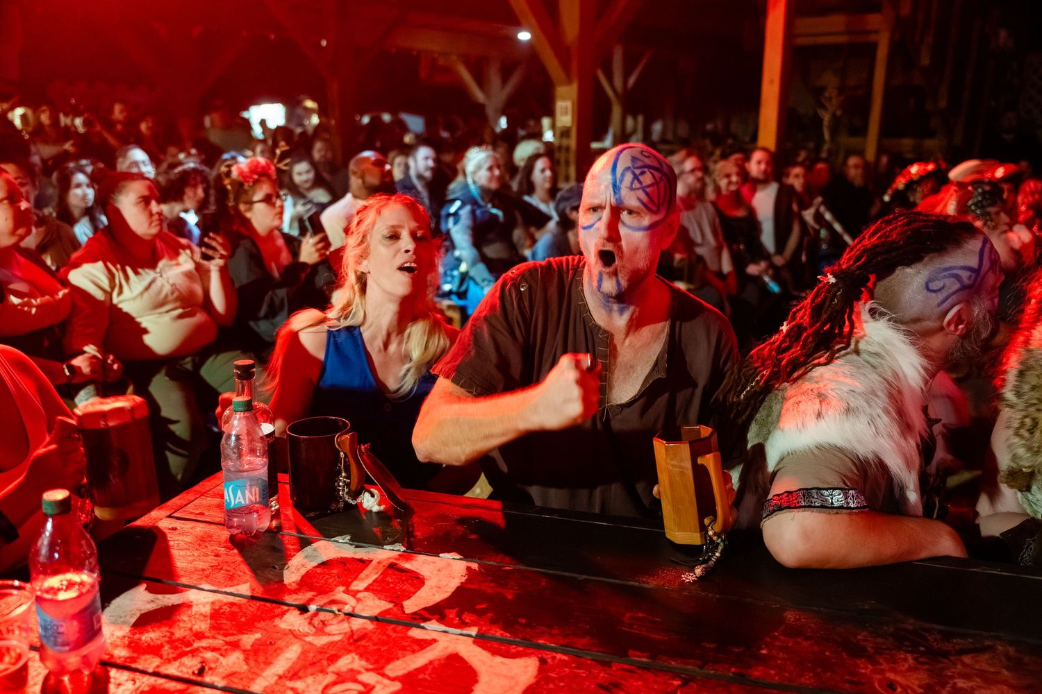 A crowd of people dancing and celebrating in a nightclub bathed in red lighting.