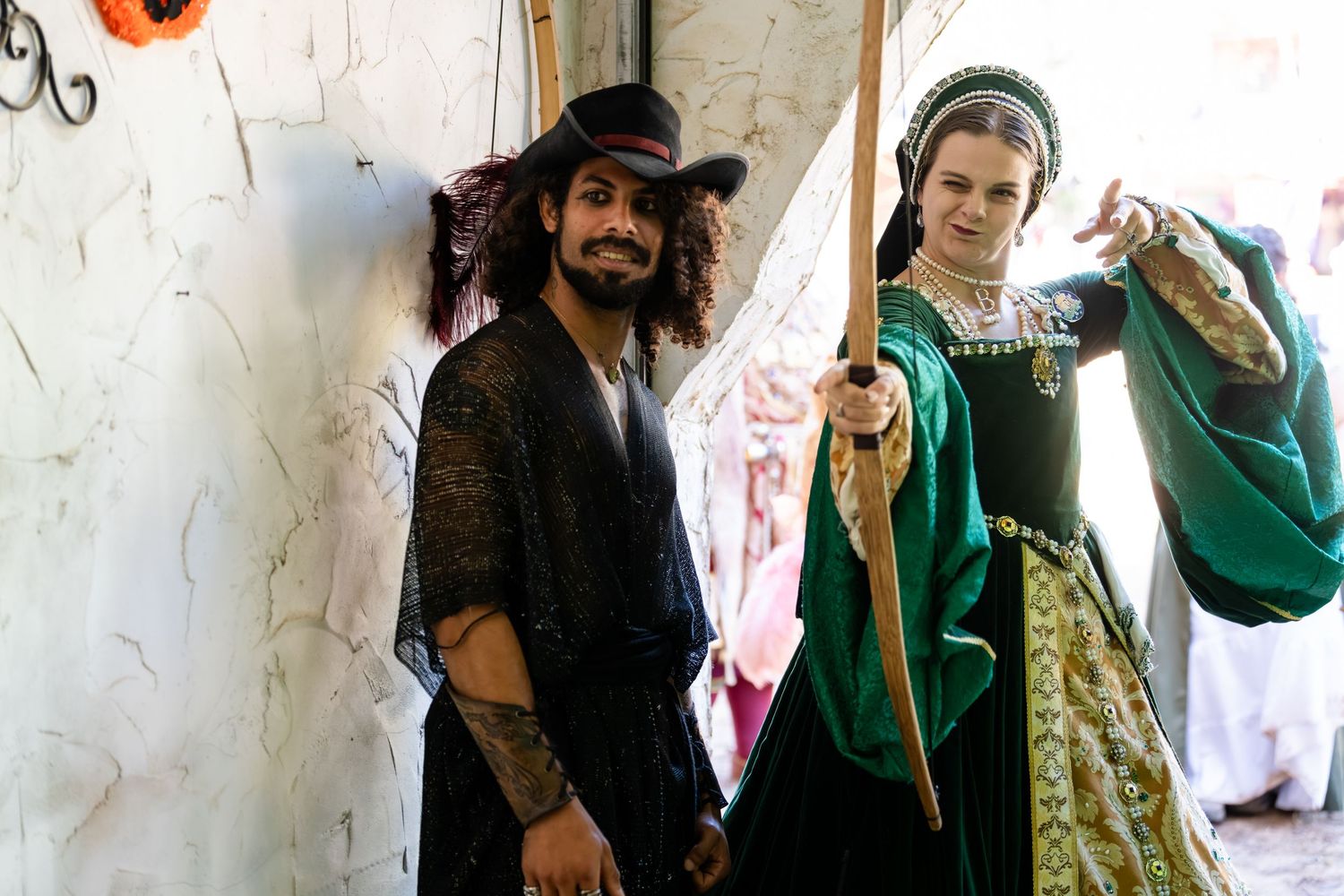 A group of people in medieval costumes pose against a white wall during a historical reenactment event.