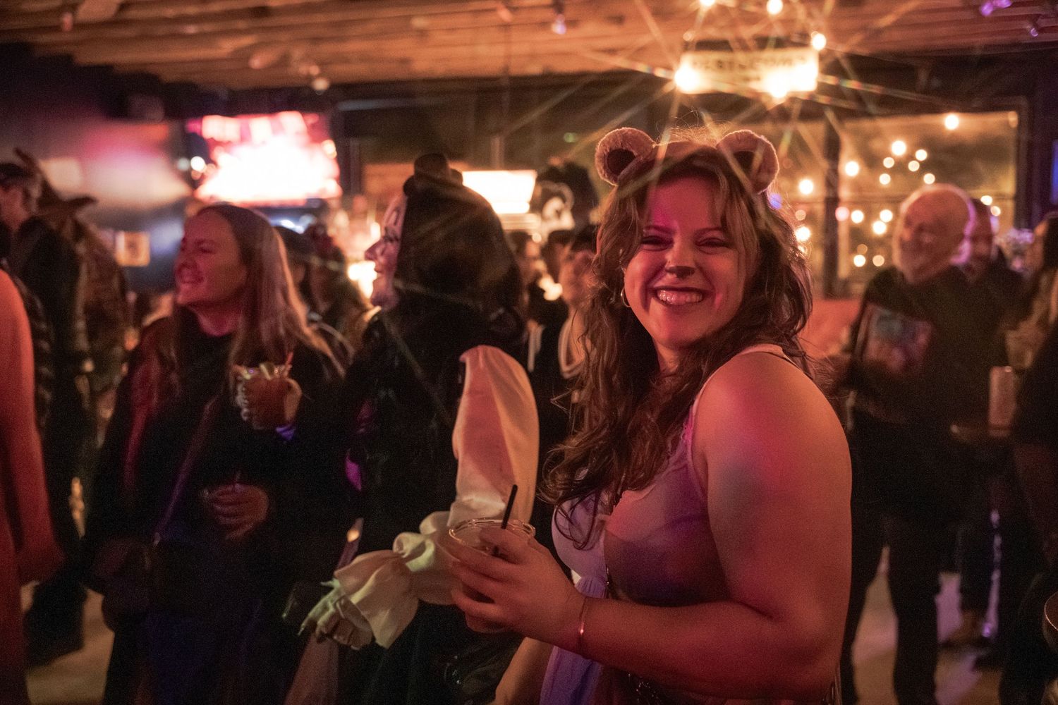 People dancing and socializing at a dimly lit nightclub or party venue with festive lighting and a lively atmosphere.