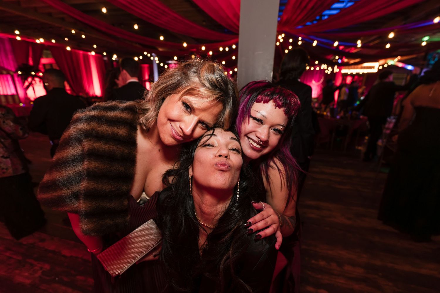 People dancing and enjoying themselves at a nightclub with red lighting and festive decorations.