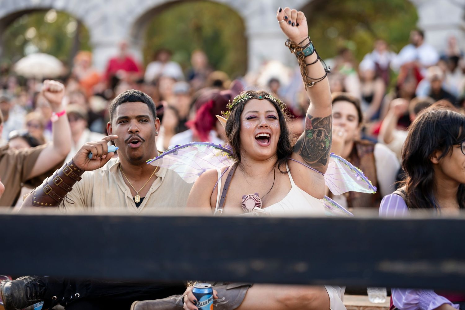 Excited festival crowd cheers and dances with raised arms at an outdoor summer music event.