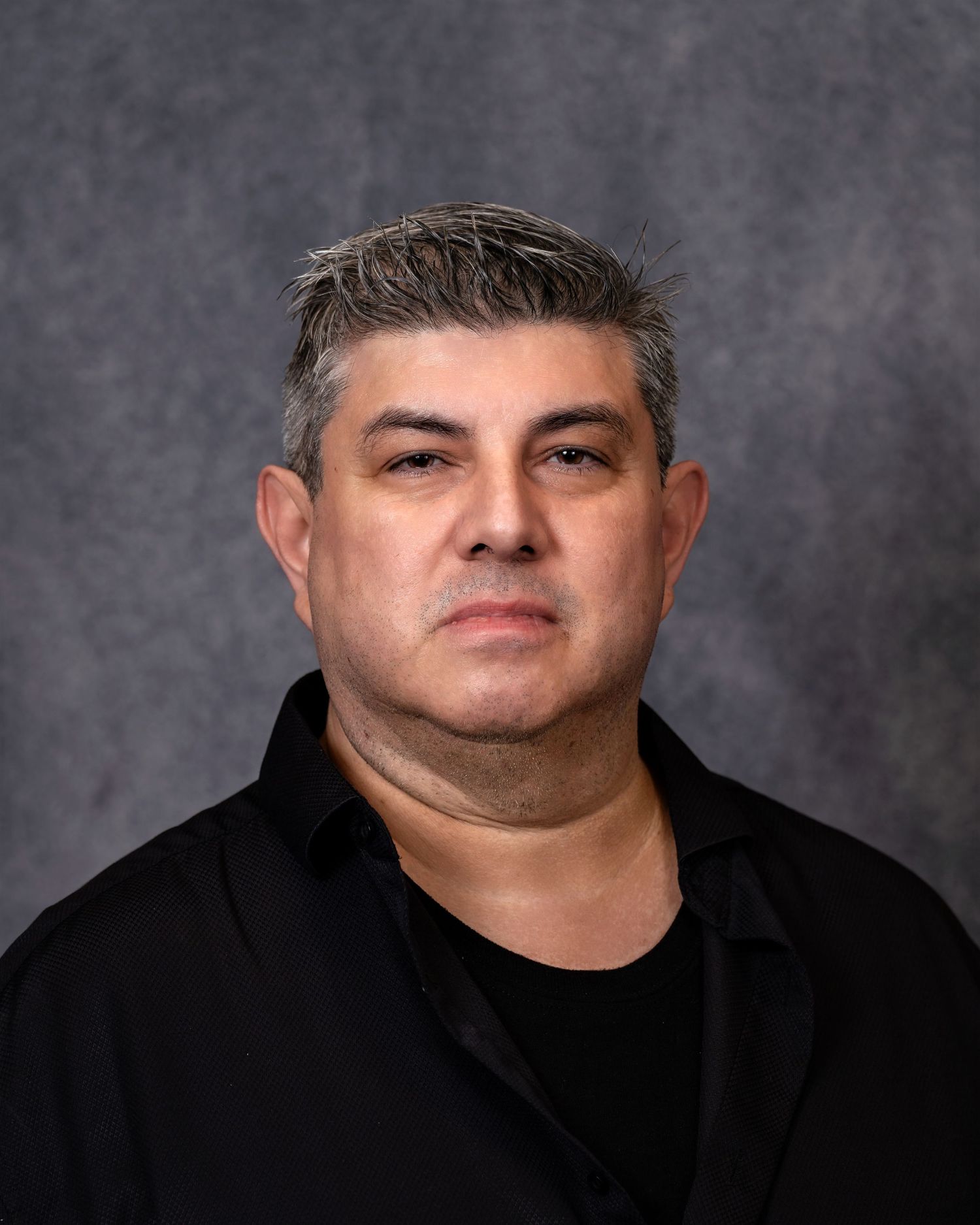 Middle-aged man with salt-and-pepper hair wearing a black shirt, posing for a professional headshot photo.